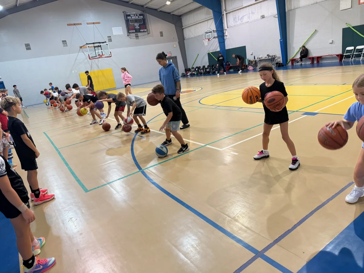 Clinic players practicing basketball dribbling drills with coaches